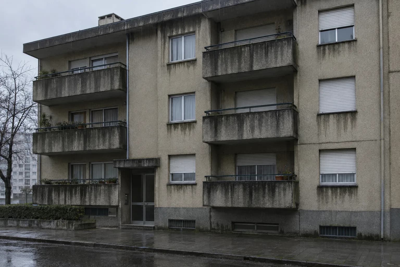 Fachada de um prédio no Porto em dia de chuva, com escorrências escuras por baixo das varandas e das janelas
